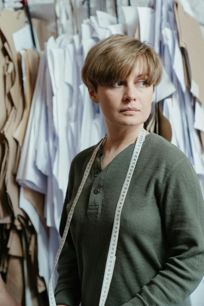 pexels-photo-4622409-4622409 A fashion designer stands in a studio surrounded by paper patterns, representing creativity and craftsmanship.