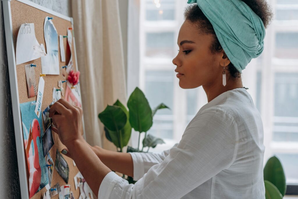 pexels-photo-6932014-6932014 Woman creating a vision board with images in a stylish home setting, showcasing creativity and focus.
