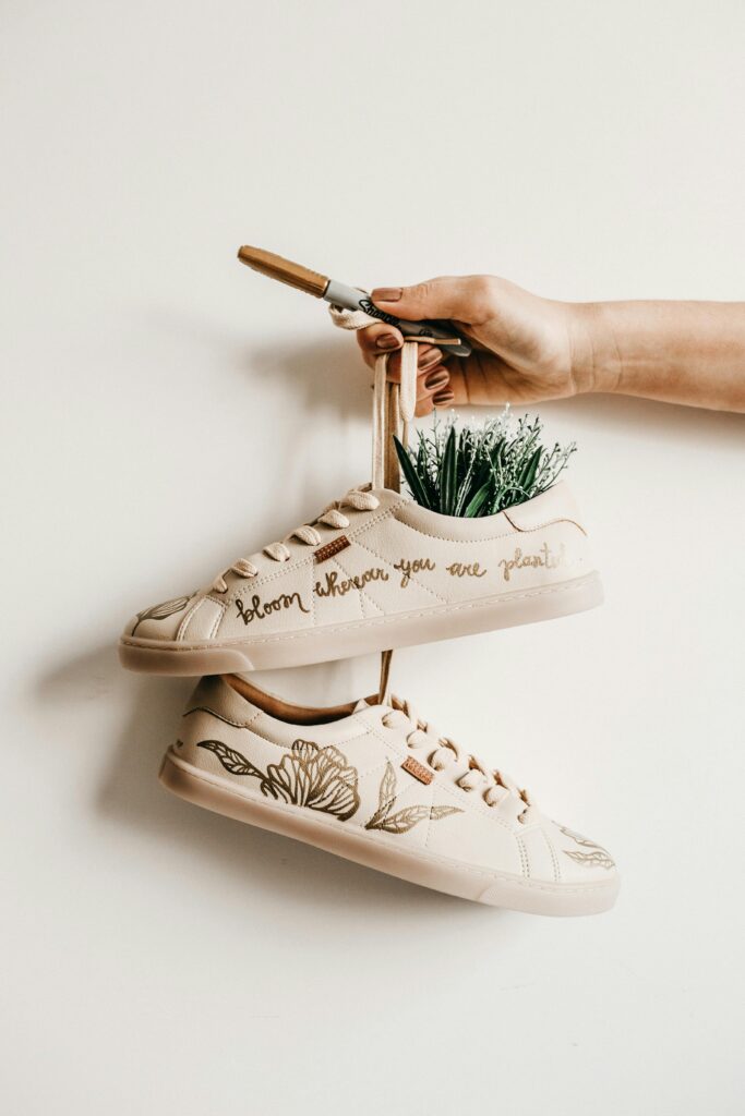 pexels-photo-3194609-3194609 Hand holding decorated shoes with plant embroidery and creative quote design.