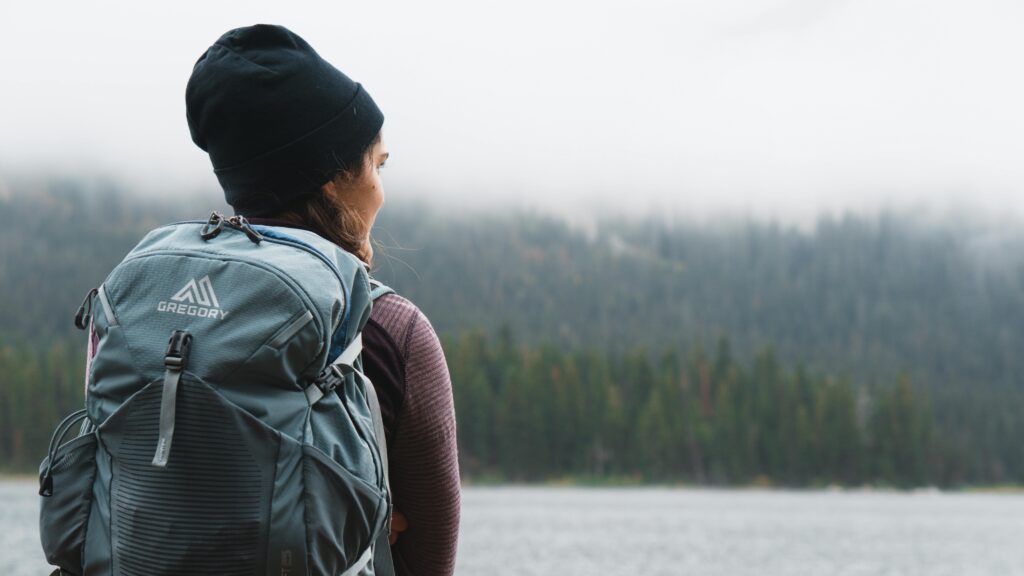 pexels-photo-3334048-3334048 Woman with backpack overlooking a foggy forest by a lake, capturing tranquility and exploration.